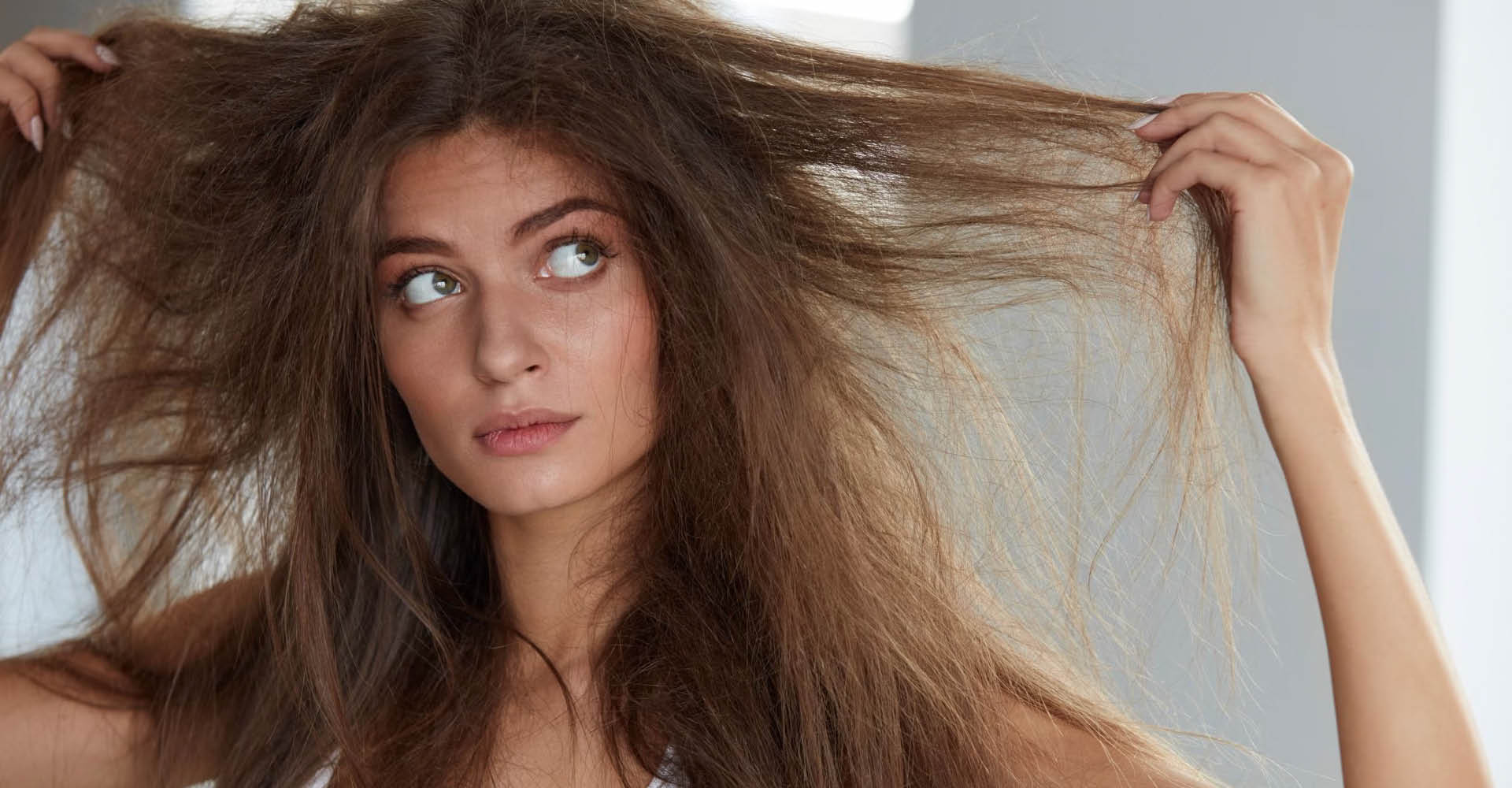 immagine di una ragazza con  capelli molto danneggiati. Si tira i capelli molto crespi a destra e sinistra
